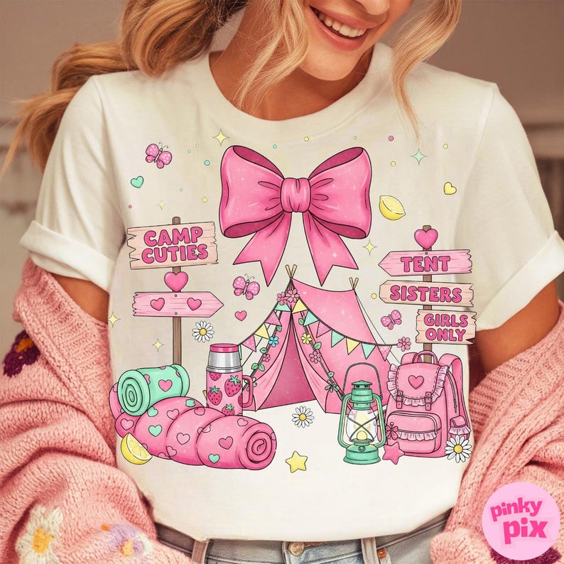 May include: White t-shirt featuring a pink bow and camping graphics. The design includes a pink tent, a backpack, a lantern, and the text "Camp Cuties" and "Tent Sisters Girls Only". The shirt has a whimsical, cute style.