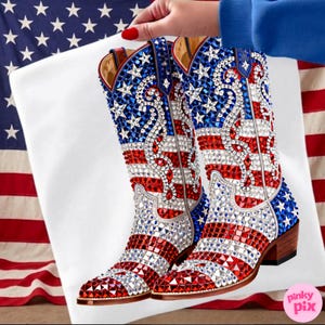 May include: A pair of bedazzled cowboy boots with a patriotic American flag design. The boots feature red, white, and blue rhinestones arranged in stripes and stars. The boots have a brown heel and are held against a white background with an American flag.