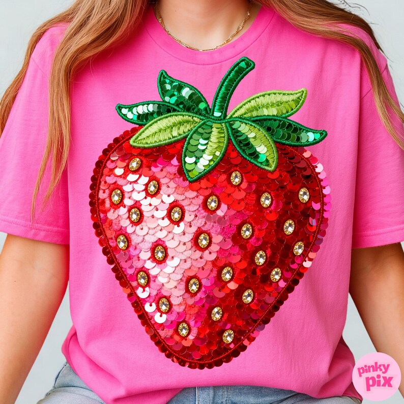 K&ouml;nnte beinhalten: Ein pinkfarbenes T-Shirt mit einem gro&szlig;en, paillettenbesetzten Erdbeermotiv. Die Erdbeere ist rot mit goldenen Akzenten und gr&uuml;nen Paillettenbl&auml;ttern. Das Shirt hat kurze &Auml;rmel und einen Rundhalsausschnitt.