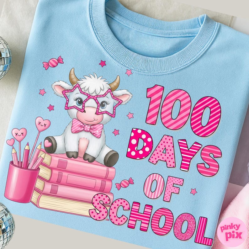 Pu&ograve; includere: Felpa azzurra con grafica di una mucca bianca con occhiali a forma di stella e un papillon rosa. Il testo "100 DAYS OF SCHOOL" &egrave; in rosa. Sono presenti anche matite e libri rosa.