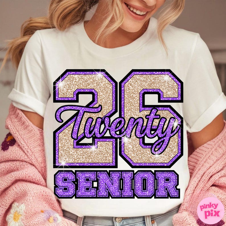 May include: White t-shirt with a glittery design featuring the number "26", the word "Twenty", and the word "Senior" in purple and gold. The design has a black outline.
