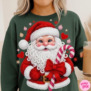 May include: A dark green sweatshirt featuring a detailed Santa Claus design. Santa is wearing a red suit and hat with white trim, holding a candy cane and a red bow. The design includes pink, gold, and red stars, hearts, and ornaments.