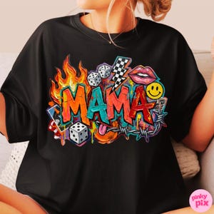 May include: Black t-shirt featuring a colorful graffiti-style design with the word "MAMA" in bold letters. The design includes flames, dice, a lightning bolt, lips, a smiley face, and barbed wire, creating a vibrant and eye-catching graphic.