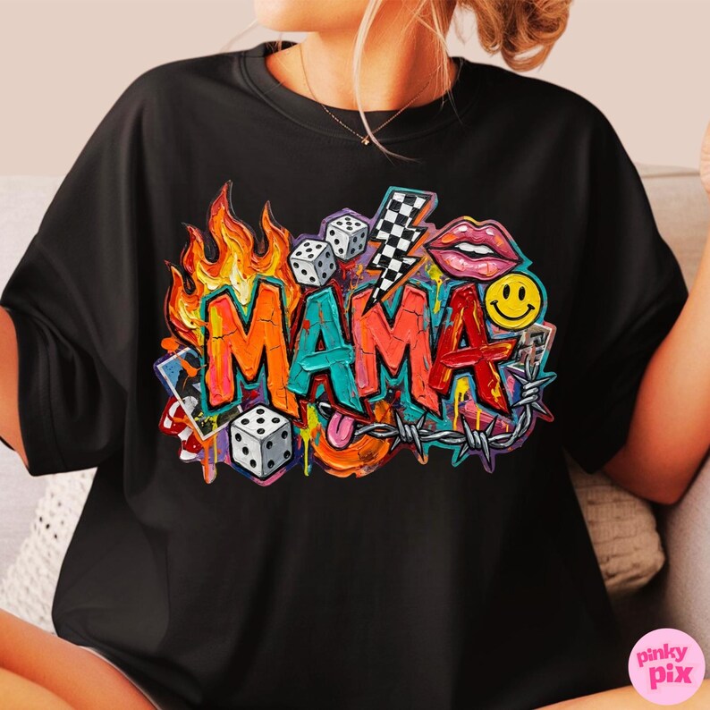 May include: Black t-shirt featuring a colorful graffiti-style design with the word "MAMA" in bold letters. The design includes flames, dice, a lightning bolt, lips, a smiley face, and barbed wire, creating a vibrant and eye-catching graphic.