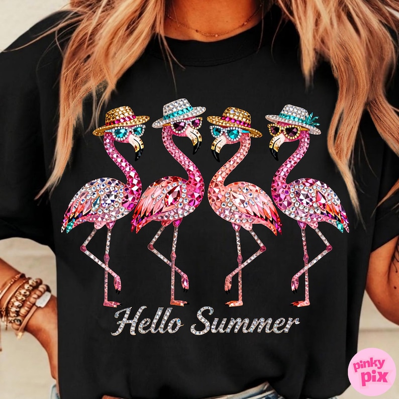 May include: Black t-shirt featuring four pink flamingo illustrations with sunglasses and hats. The flamingos are embellished with sparkling details. The text "Hello Summer" is displayed in a silver font.