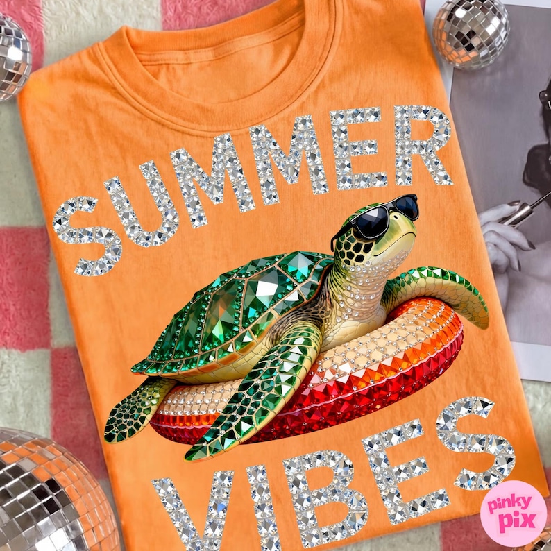 May include: Orange t-shirt with the words "SUMMER VIBES" in rhinestone lettering. A bejeweled turtle wearing sunglasses floats on a red, orange, and yellow inflatable ring. Two disco balls are on either side of the shirt.