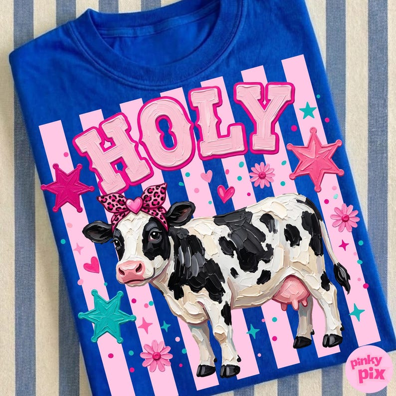 May include: A royal blue t-shirt featuring a cow illustration with a leopard print headband. The word "HOLY" is printed in pink above the cow. Pink stars, hearts, and flowers decorate the shirt.