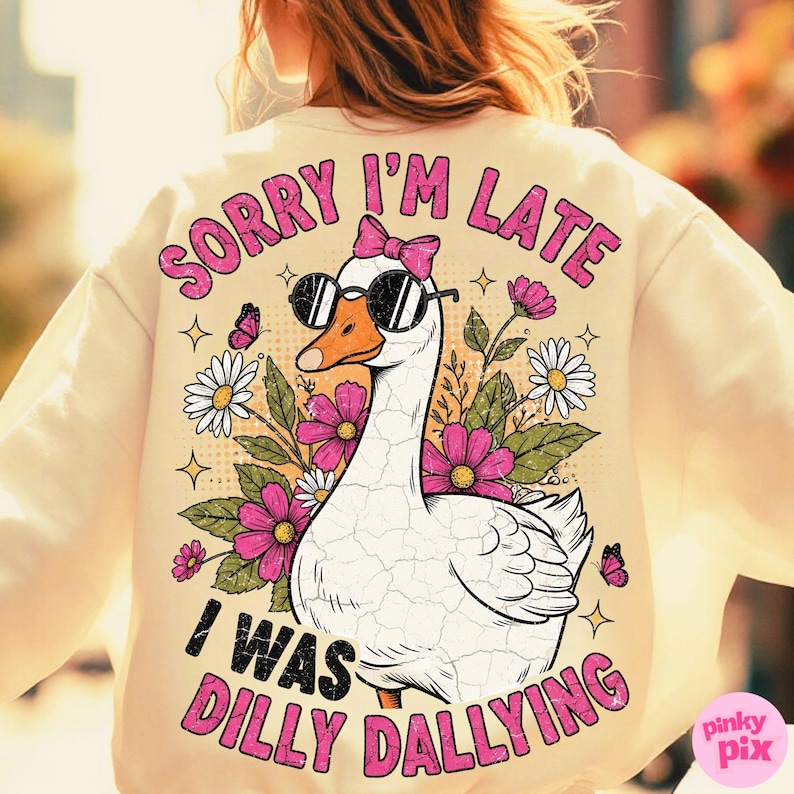 K&ouml;nnte beinhalten: Cremefarbenes Sweatshirt mit einer Grafik einer Gans mit Sonnenbrille und rosa Schleife. Der Text lautet "SORRY I'M LATE I WAS DILLY DALLYING" in Rosa. Das Design umfasst Blumen und Schmetterlinge.