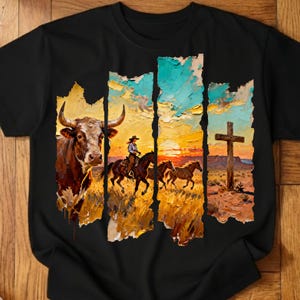 May include: Black t-shirt featuring a Western-themed graphic. The design includes a bull, a cowboy on horseback, and a cross, set against a sunset backdrop. The artwork has a textured, painted appearance.