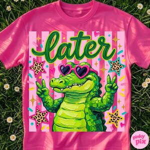 May include: Pink t-shirt featuring a cartoon alligator wearing heart-shaped sunglasses and giving a peace sign. The word "later" is written in green script above the alligator. The design includes stars and stripes.