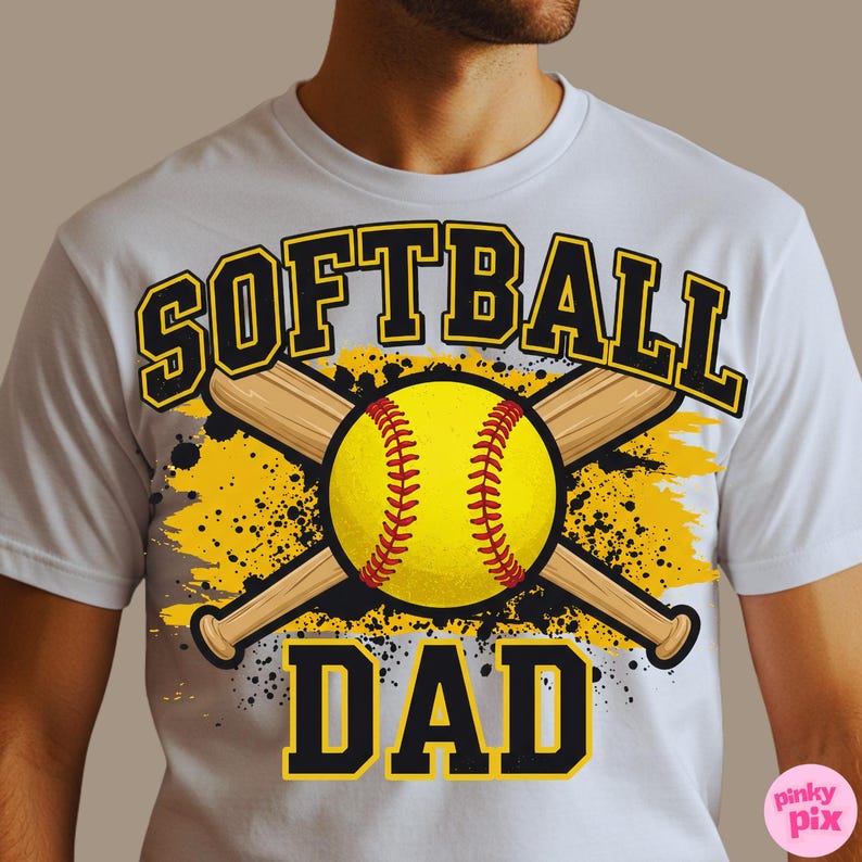 May include: White t-shirt with a softball graphic. The design features a yellow softball with red stitching, crossed wooden bats, and the words "SOFTBALL DAD" in black and yellow lettering. The background has yellow and gray splatter effects.