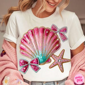 May include: White t-shirt featuring a sequined seashell design in shades of pink and teal, adorned with pearls and rhinestones. Two pink sequined bows and a starfish complete the design. The text "pinky pix" is in the bottom right corner.