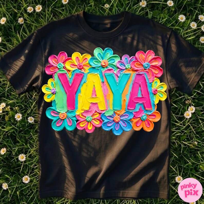 May include: Black t-shirt with the word "YAYA" in bright pink, yellow, and teal, surrounded by colorful, textured flowers. The flowers have a 3D effect, with shades of pink, yellow, blue, and orange.