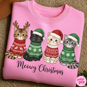 以下が含まれることがあります： ピンク色のスウェットシャツ。クリスマスセーターと帽子をかぶった4匹の漫画の猫が描かれています。猫は雪の結晶とトナカイのデザインの赤と緑のセーターを着ています。「Meowy Christmas」の文字が下に印刷されています。