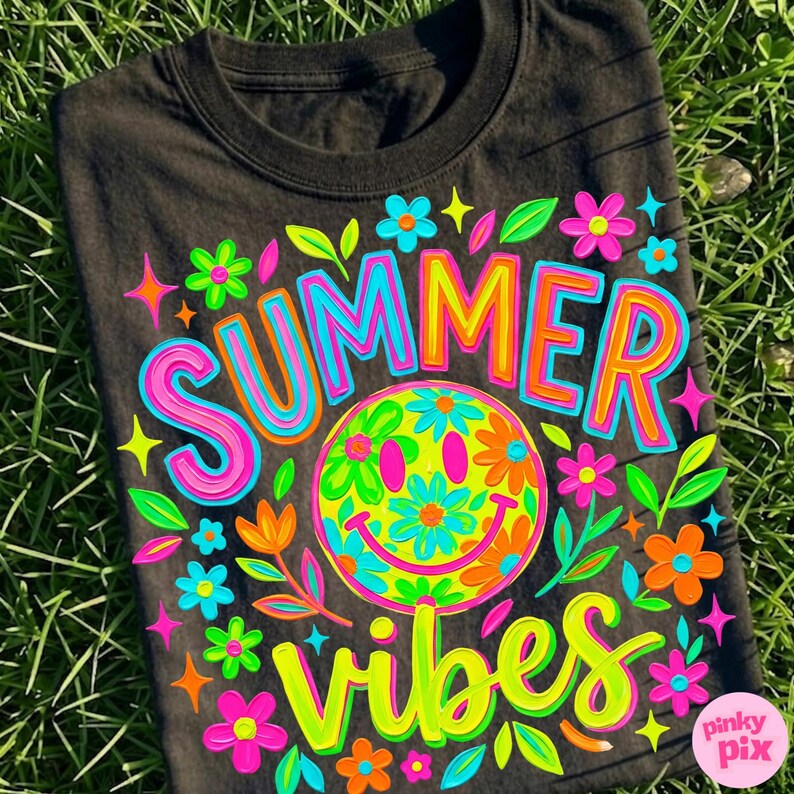 May include: Black t-shirt with a colorful "SUMMER VIBES" graphic. The design features a smiley face with flower details, surrounded by flowers and stars in bright neon colors. The shirt is displayed on a bed of green grass.