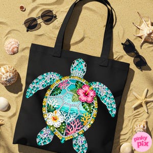 May include: Black tote bag featuring a colorful sea turtle design. The turtle has a turquoise and crystal-like shell with a tropical scene, including pink and white flowers, coral, and ocean waves. Sunglasses, seashells, and a starfish are scattered around the bag on a sandy surface.