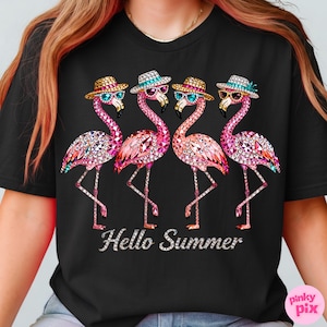 May include: Black t-shirt featuring four bejeweled flamingo illustrations wearing hats and sunglasses. The flamingos are pink with crystal accents. The text "Hello Summer" is displayed in silver script below the flamingos.