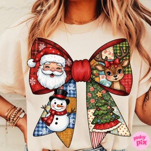 Könnte beinhalten: Cremefarbenes T-Shirt mit einem großen, farbenfrohen Schleifendesign mit weihnachtlichen Illustrationen. Die Schleife zeigt den Weihnachtsmann, ein Rentier, einen Schneemann und einen Weihnachtsbaum. Das Design enthält Karomuster, Blumenmuster und Patchwork.