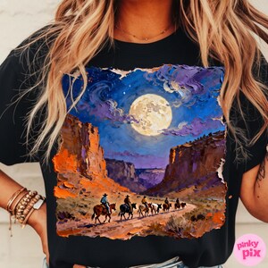 May include: Black t-shirt featuring a vibrant, impressionistic painting of a desert canyon scene under a full moon. Cowboys on horseback ride along a path, with the night sky filled with stars and clouds. The artwork has a textured, painted look.