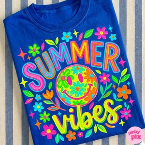 May include: A royal blue t-shirt with a colorful graphic design. The design features the words "SUMMER VIBES" in bright, outlined letters, a smiley face made of flowers, and various floral accents. The shirt is a casual summer style.