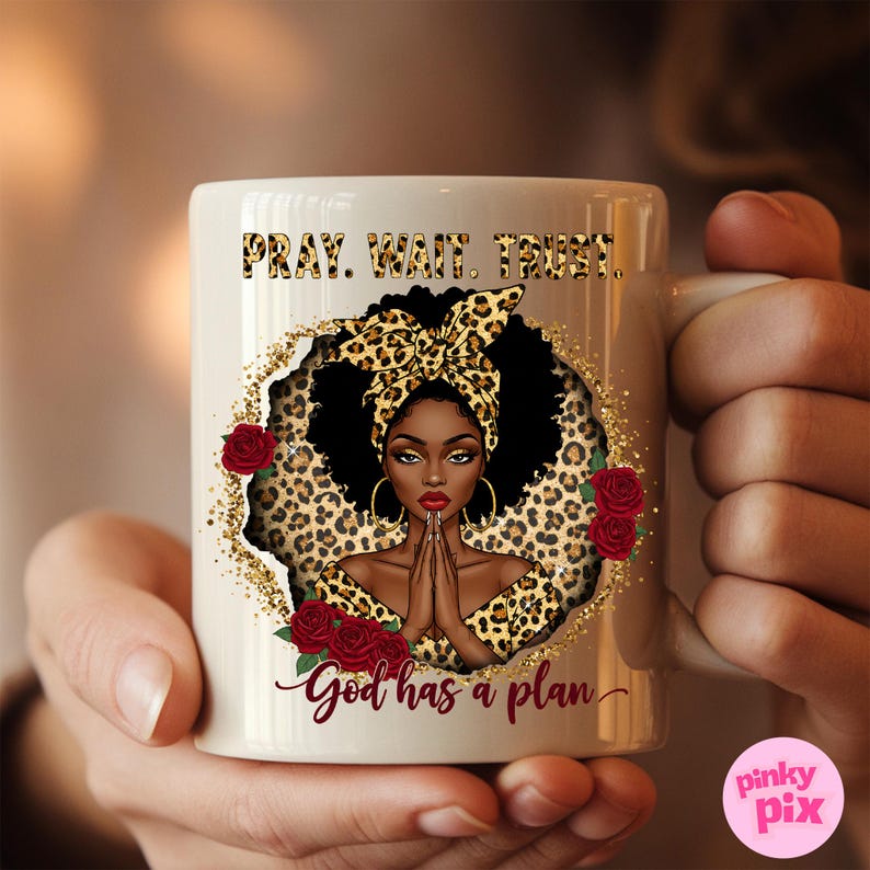 May include: White ceramic mug with a black woman with a leopard print headscarf and dress. The mug has the text "Pray. Wait. Trust. God has a plan." in black lettering.
