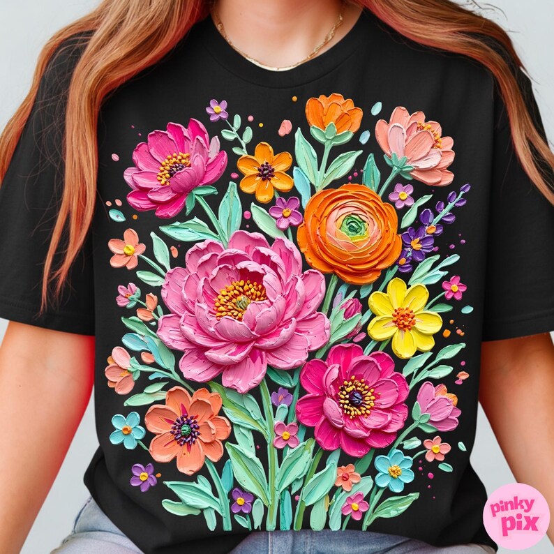 May include: Black t-shirt featuring a vibrant floral design. The design includes large pink peonies, orange, yellow, and purple flowers, and green leaves. The flowers have a textured, 3D appearance, creating a lively and colorful aesthetic.