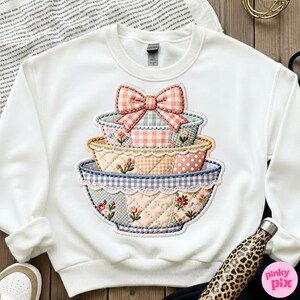 Puede incluir: Sudadera blanca con un dise&ntilde;o de cuencos apilados y un lazo. Los cuencos tienen un patr&oacute;n de patchwork con detalles florales y de cuadros en rosa, azul y amarillo. Un gr&aacute;fico encantador de inspiraci&oacute;n vintage.