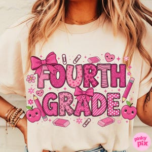 May include: A cream-colored t-shirt featuring the words "FOURTH GRADE" in large, pink, decorative letters. The design includes bows, hearts, apples, pencils, erasers, and paper clips. The words and graphics are in various pink patterns.