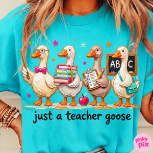 May include: A turquoise t-shirt features a graphic of four cartoon geese, each with a different school-related item. The geese are holding books, clipboards, and a chalkboard. The text "just a teacher goose" is printed below the geese.