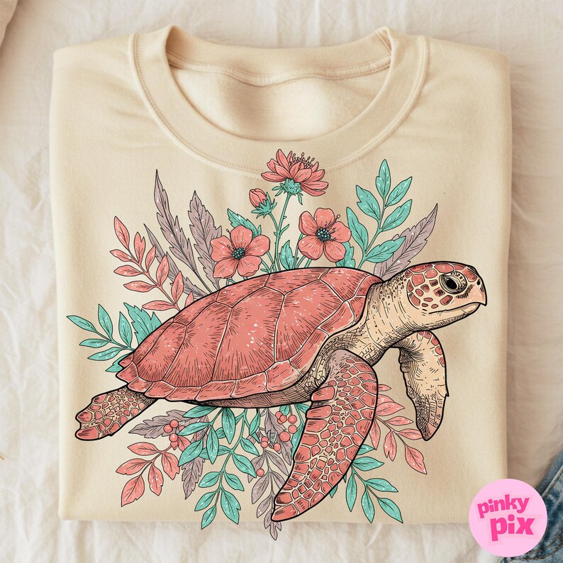 May include: A cream-colored sweatshirt with a graphic of a sea turtle surrounded by pink and blue flowers and leaves. The turtle is pink and has a detailed shell.