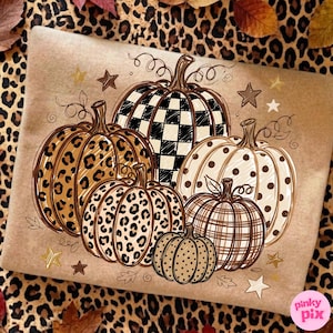 Puede incluir: Una sudadera color canela con un estampado gráfico de cinco calabazas con varios patrones, incluyendo cuadros vichy en blanco y negro, estampado de leopardo y lunares, decorado con pequeñas estrellas y zarcillos.