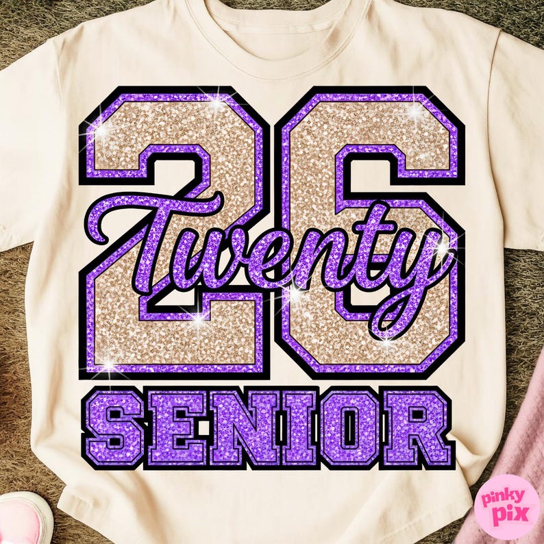 May include: Cream-colored t-shirt with a large graphic design. The design features the number "23" in a glittery gold color, outlined in purple and black. The word "Twenty" is written in a cursive font, and the word "Senior" is at the bottom.