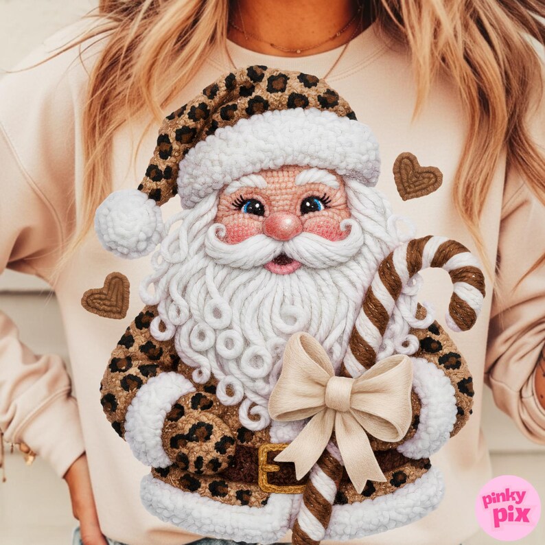 May include: A beige sweatshirt featuring a detailed Santa Claus design. The Santa Claus has a white beard, blue eyes, and a pink nose. He wears a leopard print hat and coat. A brown and white candy cane and a cream bow are also featured.