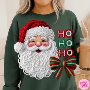 May include: Dark green sweatshirt featuring a crocheted Santa Claus design with a red hat, white beard, and the words "HO HO HO" in red and green. A red, green, and gold bow is also part of the design. The sweatshirt is a festive holiday item.
