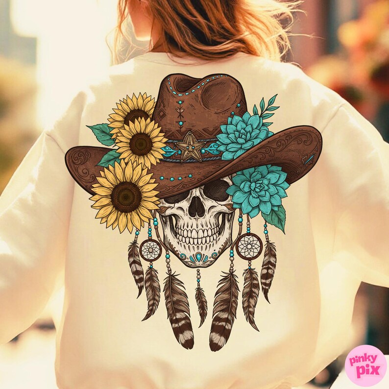 Op de afbeelding: Cr&egrave;mekleurige sweatshirt met een gedetailleerde afbeelding op de achterkant. Het ontwerp omvat een bruine cowboyhoed versierd met zonnebloemen en turquoise bloemen, een schedel en dromenvangers met veren.