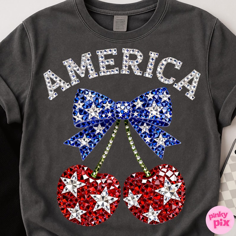 May include: Dark gray crew neck sweatshirt with the word "AMERICA" in silver rhinestones. Below the text is a blue bow with white star rhinestones and red cherry rhinestones with white star rhinestones.