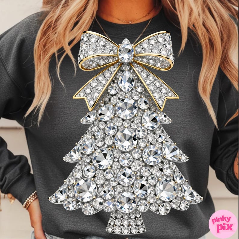May include: A dark gray sweatshirt featuring a sparkling Christmas tree design. The tree is made of numerous clear, round and oval-shaped rhinestones, with a gold bow at the top. The design is centered on the front of the shirt.