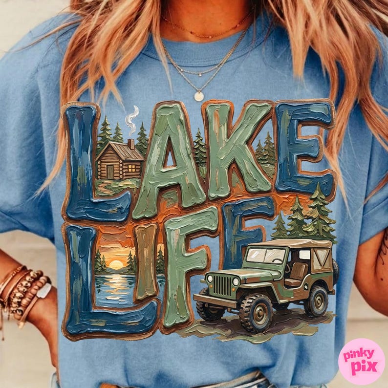 May include: A light blue t-shirt with the words "LAKE LIFE" in a textured, multi-colored design. The graphic includes a cabin, a sunset over a lake, and a green jeep.