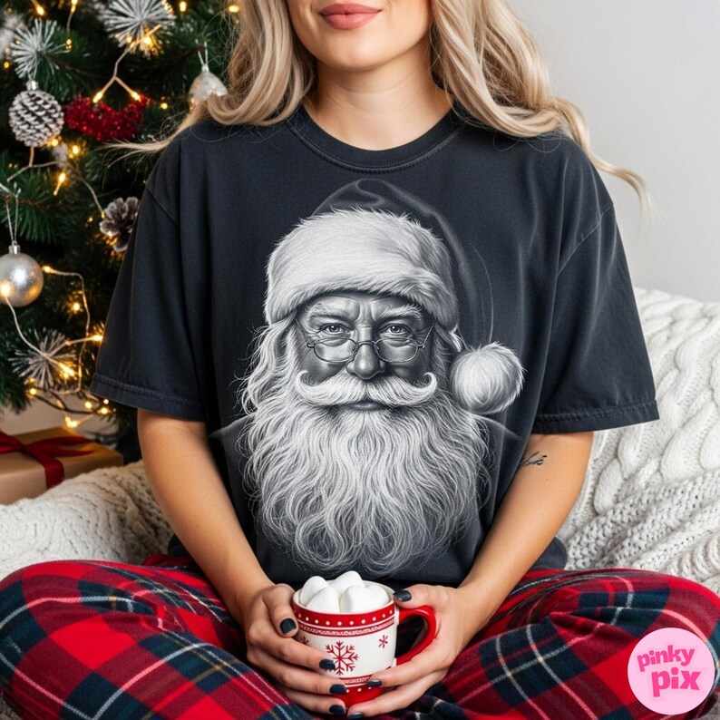 May include: Black t-shirt featuring a detailed grayscale illustration of Santa Claus with a long white beard, glasses, and a hat. The person is wearing red and black plaid pajama pants and holding a red mug with marshmallows.
