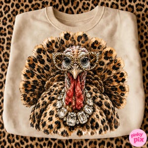 May include: A beige crewneck sweatshirt featuring a graphic of a turkey with leopard print feathers, wearing cat-eye glasses with a leopard pattern and a large crystal statement necklace. The turkey has a red wattle and a sharp beak.