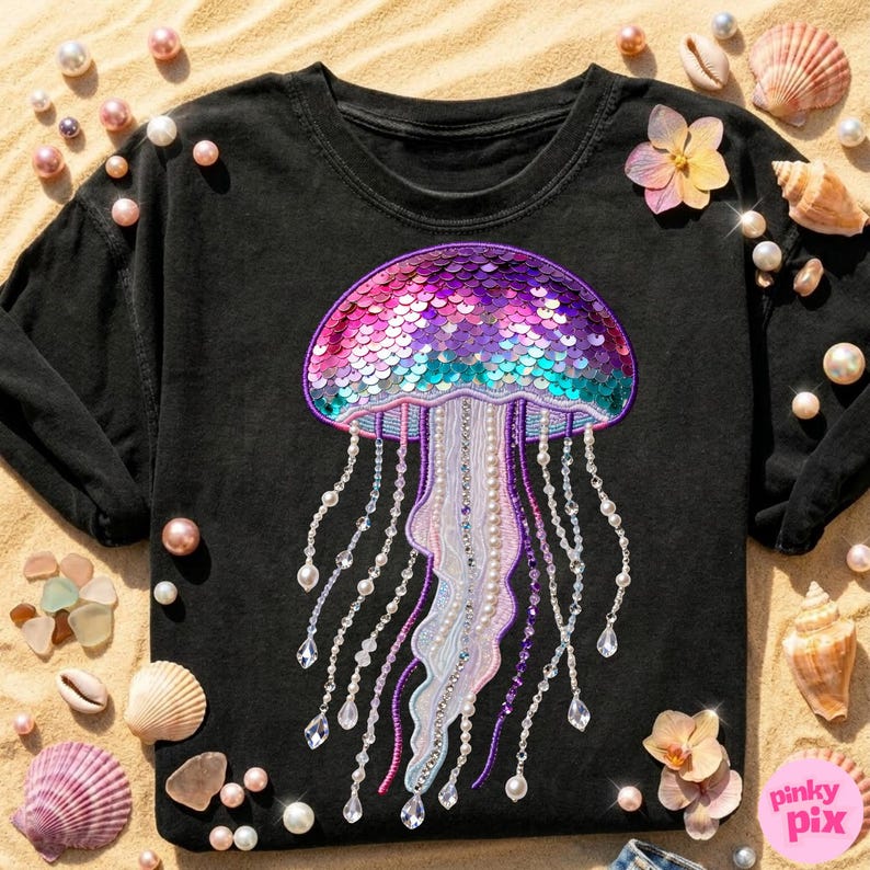 May include: Black long-sleeve shirt featuring a sequined jellyfish design in shades of pink, purple, and teal. The jellyfish has beaded tentacles and is embellished with pearls and crystals. The shirt is surrounded by seashells, pearls, and flowers.