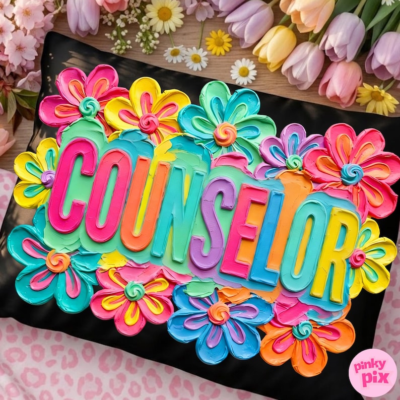 May include: A black pillow with the word "COUNSELOR" in colorful, raised lettering, surrounded by vibrant, textured flowers in shades of pink, yellow, blue, and orange. The pillow is decorated with a floral design.