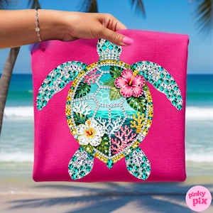 May include: A hot pink tote bag featuring a bejeweled sea turtle design. The turtle has turquoise, gold, and clear crystal accents, with a central ocean scene and hibiscus flowers. The bag is held up against a beach backdrop.