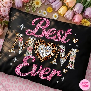 May include: Black pillowcase with the text "Best Mom Ever" in pink rhinestone lettering. The letter "M" is decorated with flowers and the heart is leopard print with a diamond center. Decorative stars and hearts are scattered around the text.