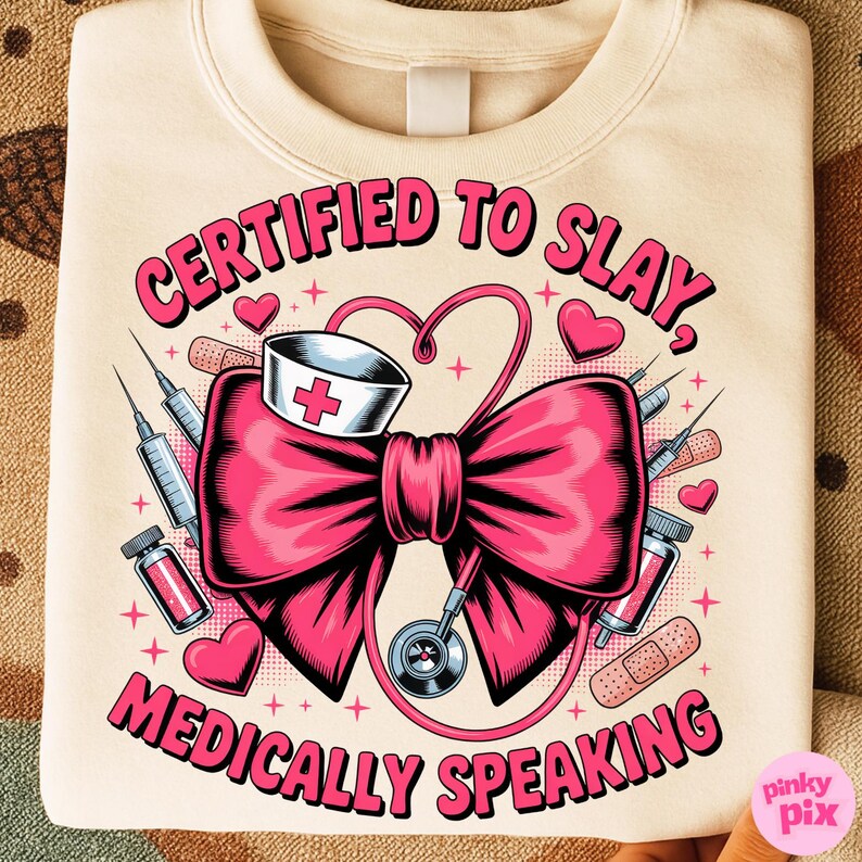 May include: Cream-colored sweatshirt with a pink graphic. The graphic features a large pink bow, a nurse's hat, a stethoscope, syringes, and the text "CERTIFIED TO SLAY, MEDICALLY SPEAKING."
