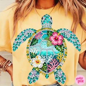 May include: Yellow t-shirt featuring a bejeweled sea turtle design. The turtle has turquoise gem wings and head, with a shell design of tropical flowers, coral, and ocean imagery. The shirt is a solid yellow color.