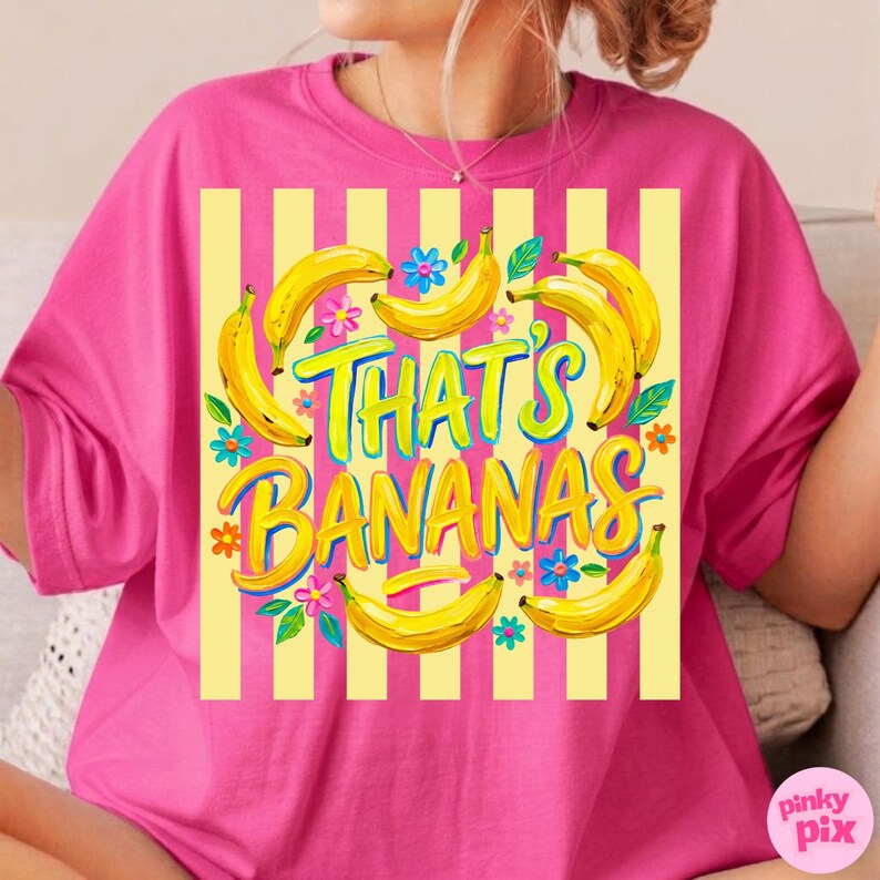 Pu&ograve; includere: Una maglietta rosa acceso con sfondo a righe gialle e bianche. La maglietta presenta una grafica di banane gialle, fiori e la scritta "THAT'S BANANAS" in un font giocoso. Il design &egrave; divertente e colorato.