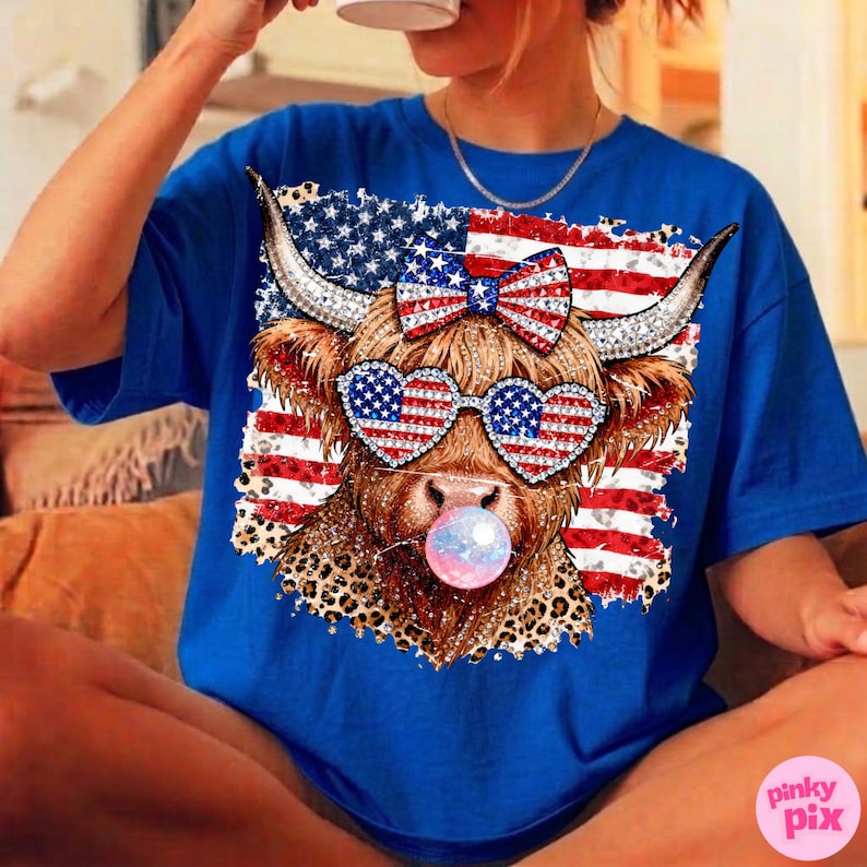 May include: Royal blue t-shirt featuring a whimsical design of a Highland cow with patriotic sunglasses and a bow, set against an American flag backdrop. The cow is blowing a bubblegum bubble. The design incorporates red, white, and blue colors.