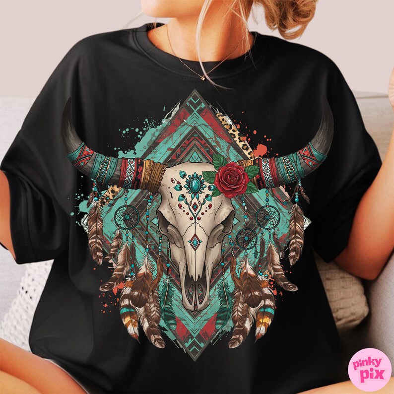 May include: Black t-shirt with a detailed graphic of a bull skull. The design incorporates turquoise, red, and brown tribal patterns, feathers, a red rose, and dream catchers, creating a bohemian aesthetic.