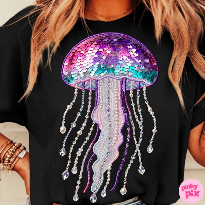 May include: Black t-shirt featuring a colorful jellyfish design. The jellyfish has a sequined, iridescent cap in shades of pink, purple, and teal. Long, beaded tentacles with pearls and crystals hang below, creating a shimmering effect. The design is detailed and eye-catching.